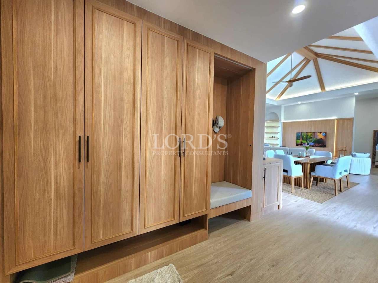 Built-in wooden wardrobe with seating bench in a modern open-plan villa interior