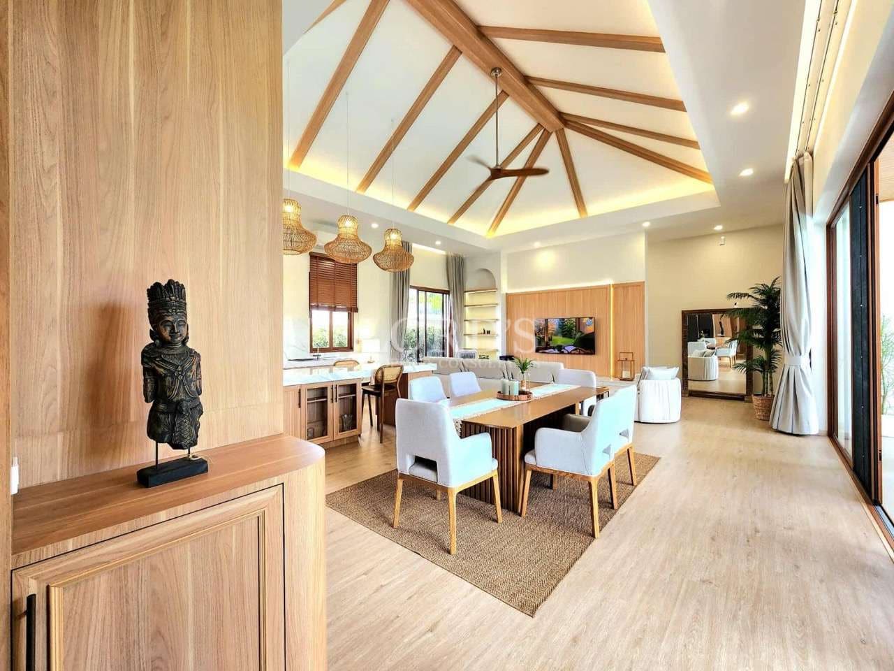 Open-plan living and dining area with vaulted wooden ceiling, modern furniture, and floor-to-ceiling glass doors