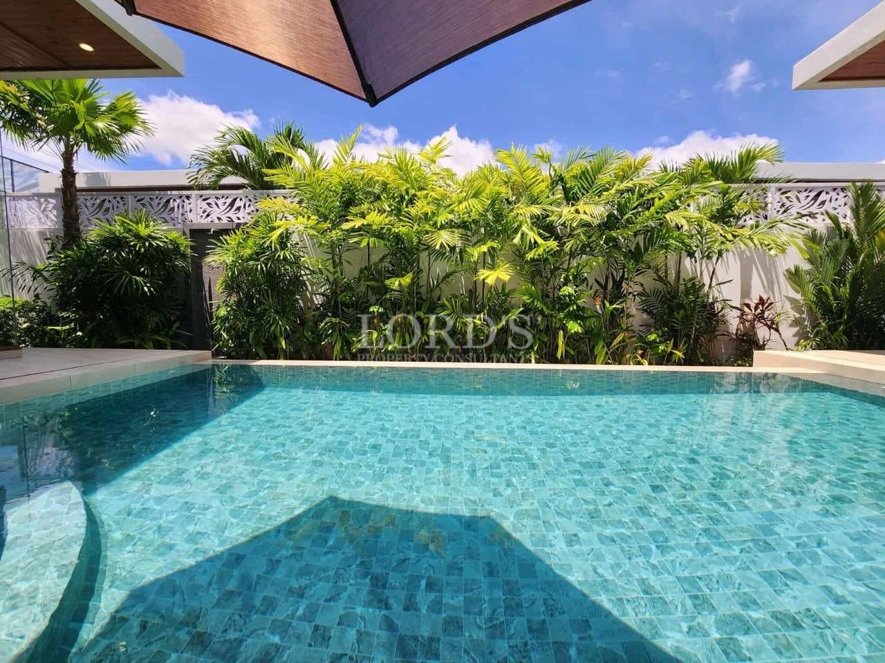Private swimming pool with crystal-clear water, tropical plants, and modern villa courtyard