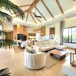 Open-plan modern living room with vaulted wooden ceiling, sectional sofa, dining area, and natural light