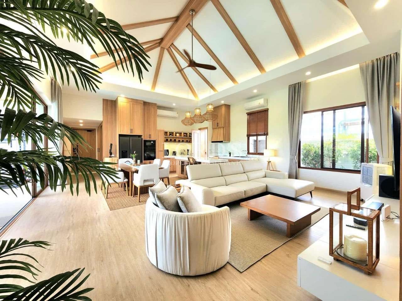 Open-plan modern living room with vaulted wooden ceiling, sectional sofa, dining area, and natural light