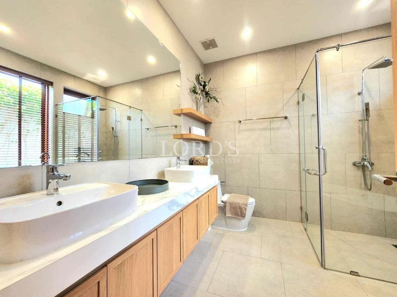 Spacious modern bathroom with double sink vanity, glass shower enclosure, large mirror, and neutral stone tiles