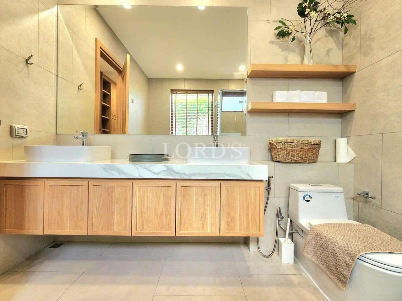 Modern bathroom vanity with wooden cabinets, marble countertop, floating shelves, and minimalist decor