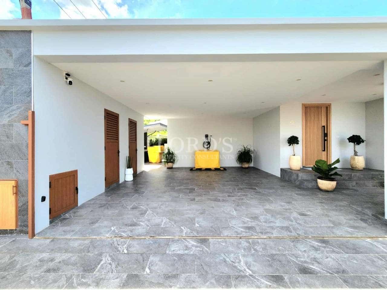 Spacious covered carport with tiled flooring, modern entrance door, and minimal landscaping