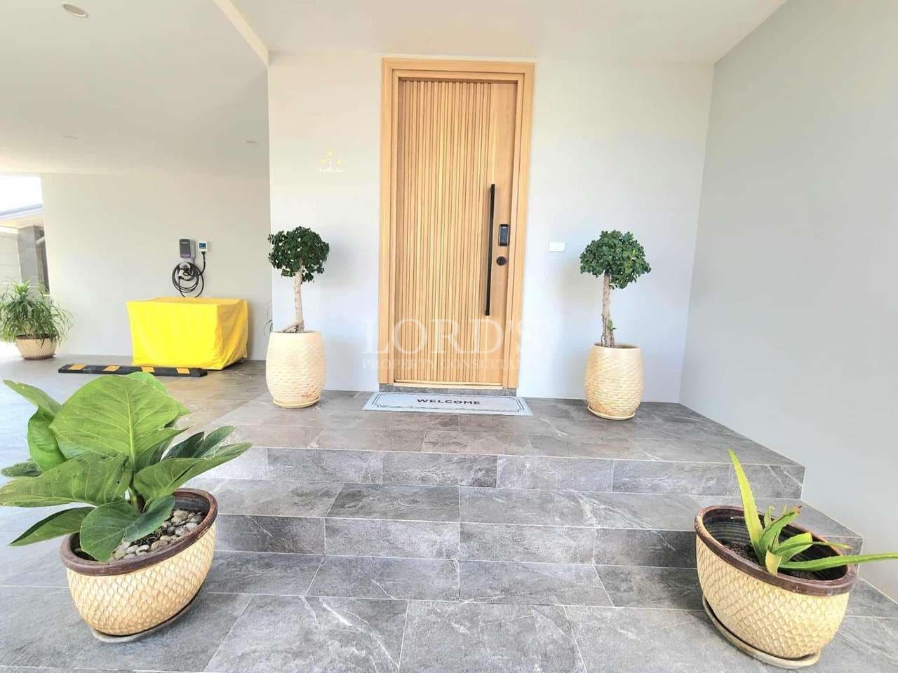 Modern home entrance with wooden front door, stone steps, and decorative potted plants