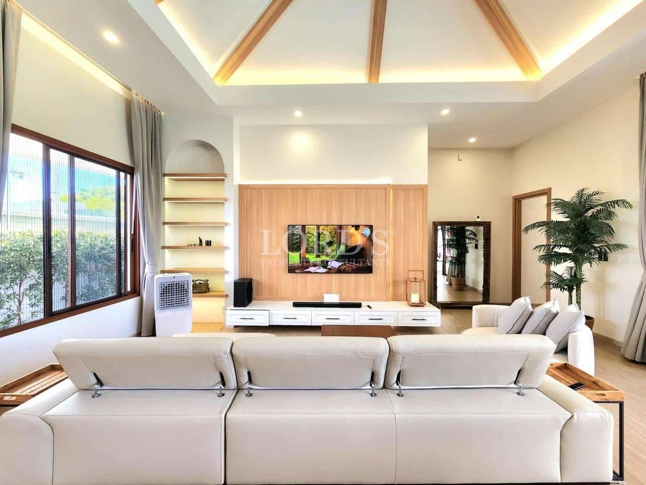Modern living room with white sofa, wooden TV feature wall, and recessed ceiling lighting