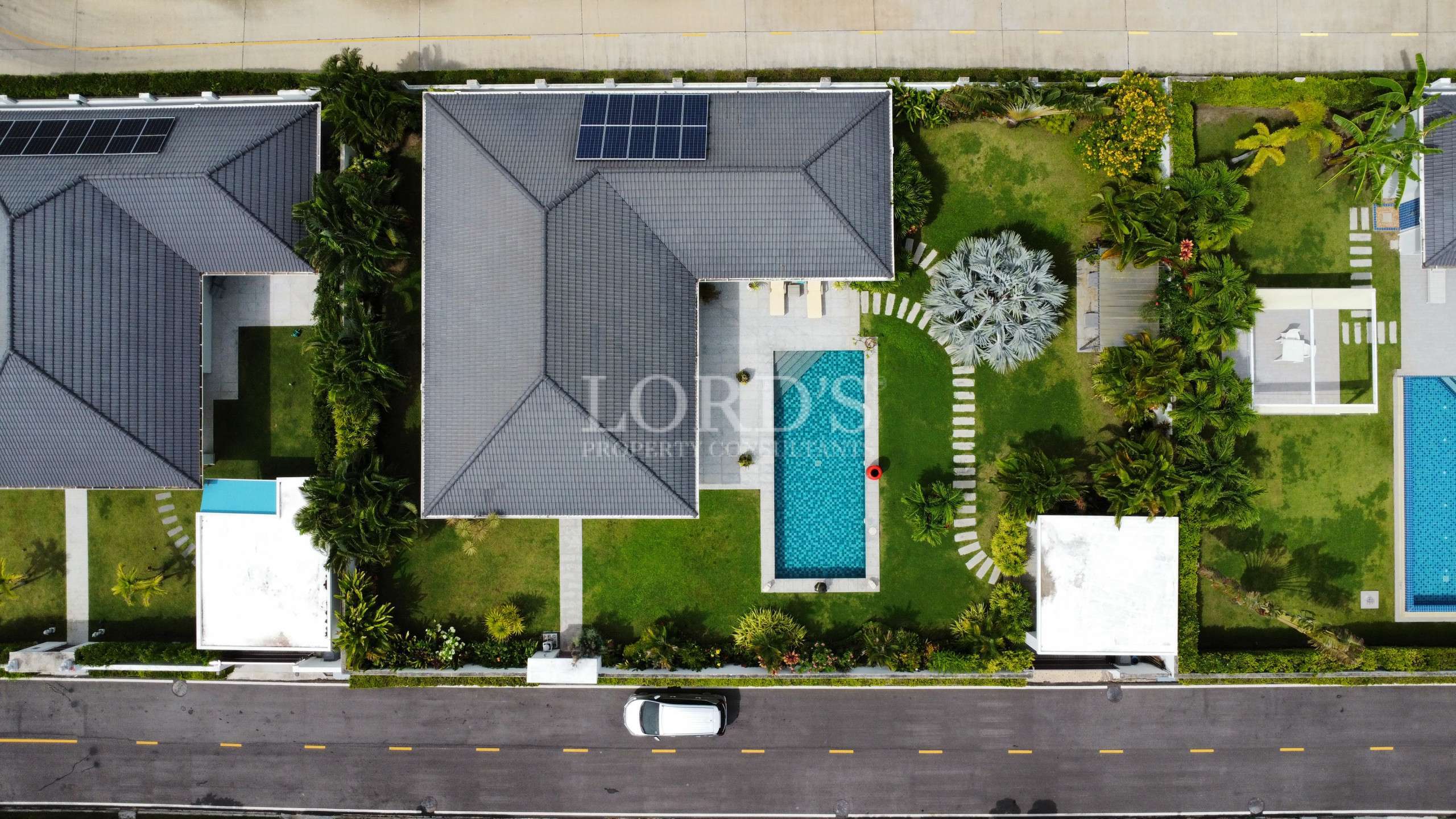 Aerial top view of a modern villa with private swimming pool, garden, and solar roof panels