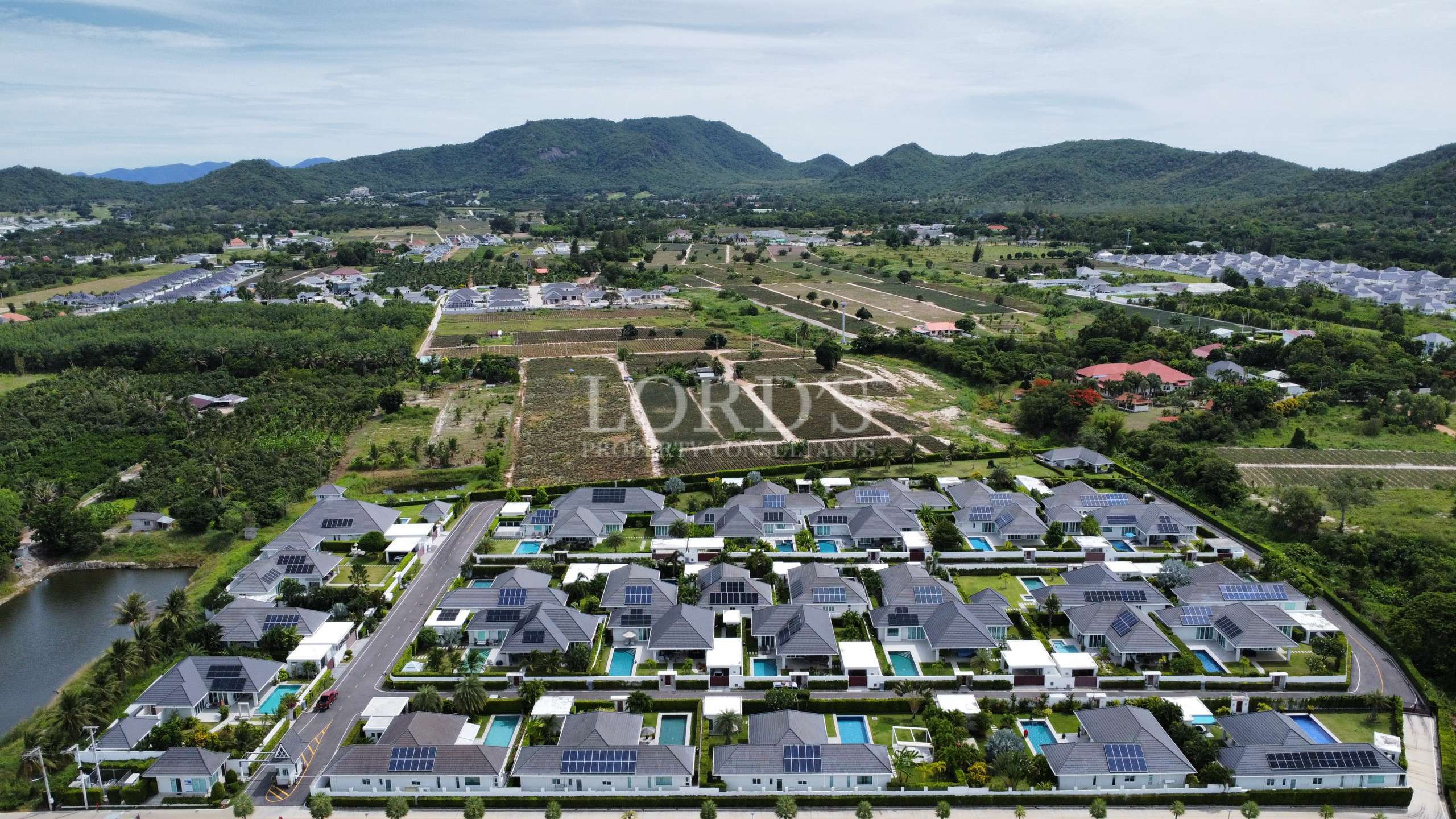Aerial view of a modern villa community with private pools and mountain backdrop