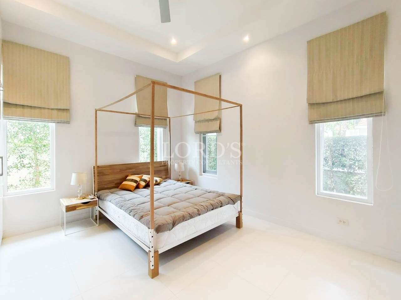 Bright minimalist bedroom with wooden four-poster bed and large windows