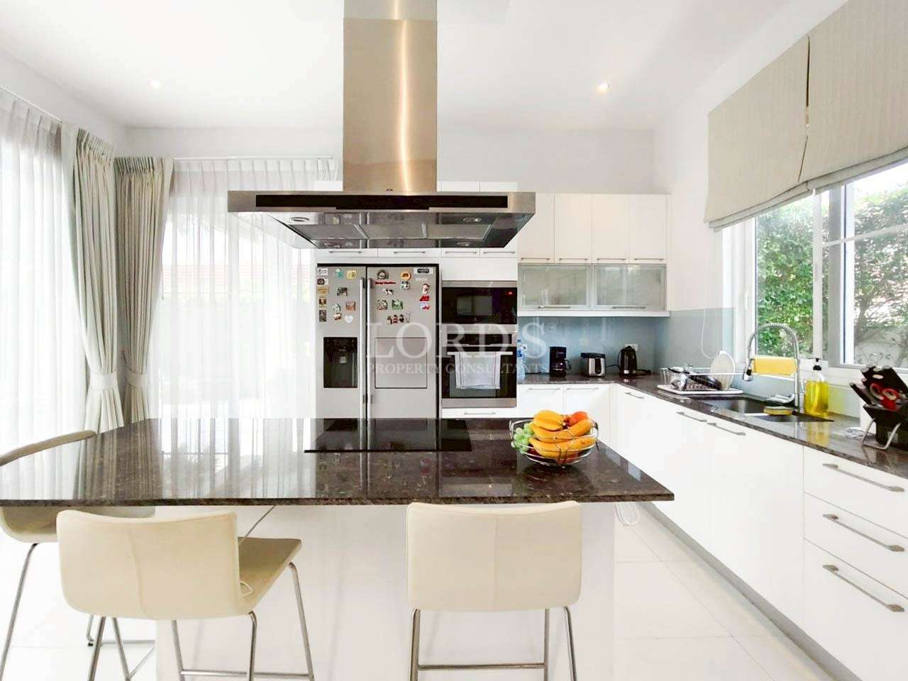 Bright modern kitchen with white cabinets, black island countertop, and stainless steel range hood