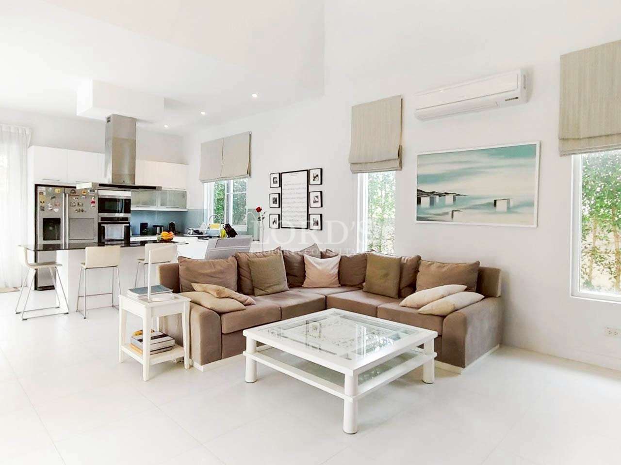 Bright open-plan living room with modern kitchen, sectional sofa, and white interior design