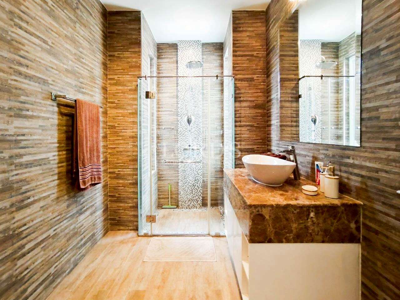 Luxury modern bathroom with glass walk-in shower, stone tile walls, and marble vanity