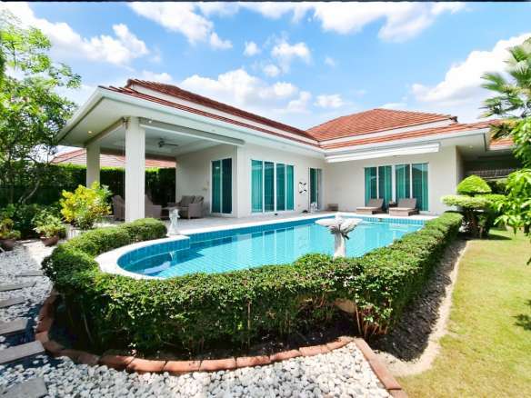 Luxury single-story villa with private swimming pool, garden hedges, and outdoor seating area.