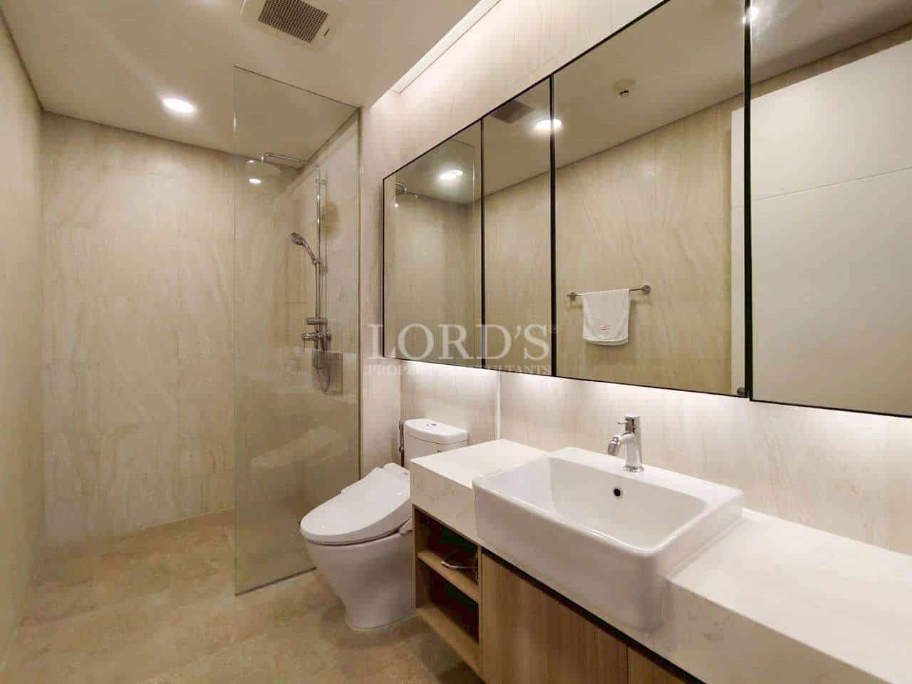 Modern bathroom with glass shower, toilet, and single sink vanity.