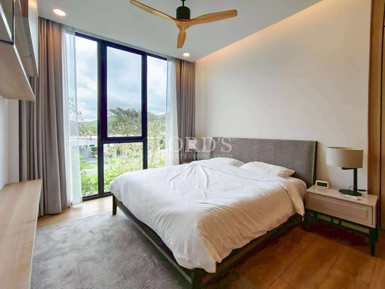 Modern bedroom with double bed, ceiling fan, and large window with green view.