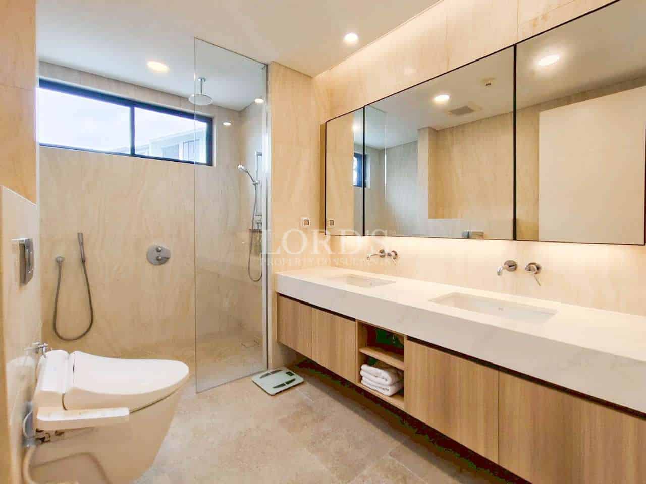 Modern bathroom with double sink vanity, glass shower, and wood-finish cabinets.