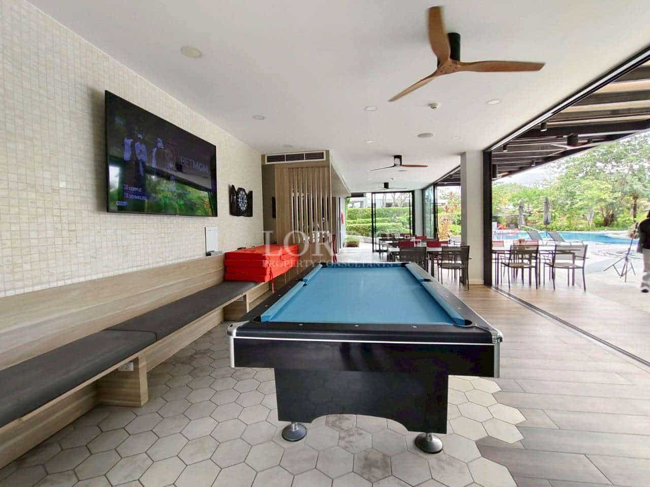 Modern recreation room with a pool table, seating area, and open-air design.