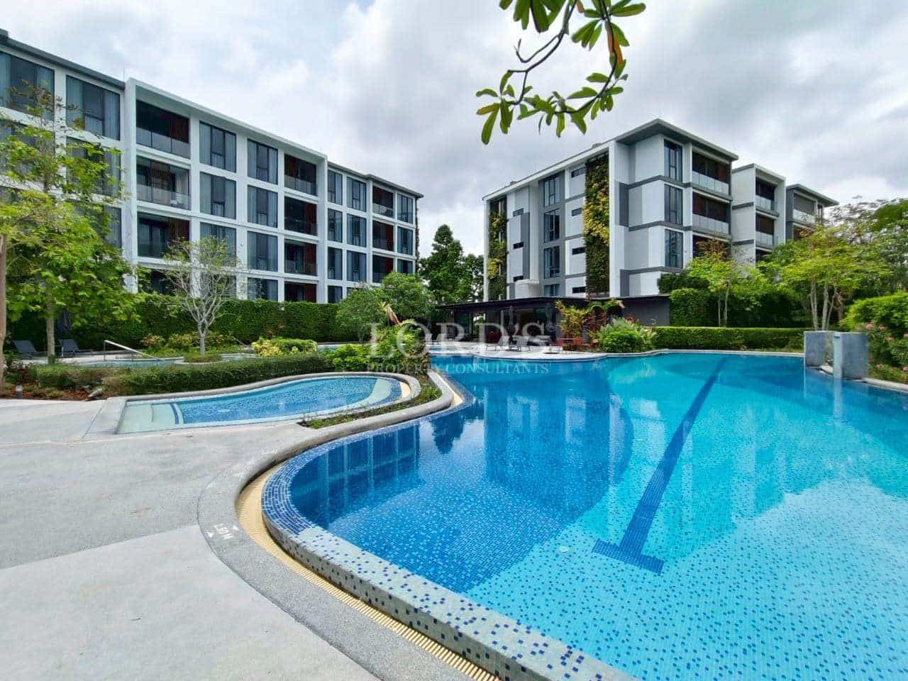 Modern condominium buildings with a resort-style swimming pool and landscaped surroundings.