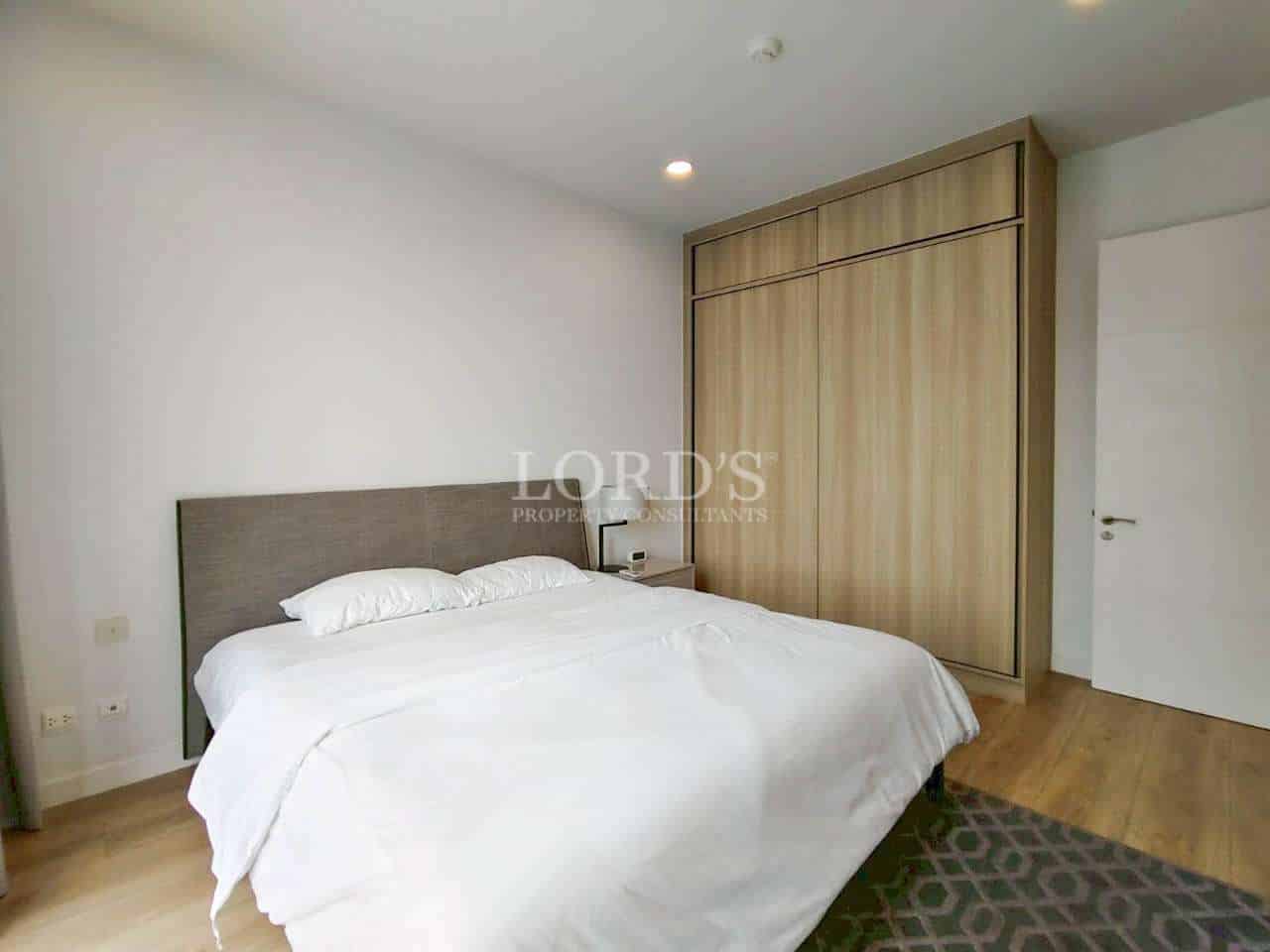 Modern bedroom with double bed, wooden wardrobe, and minimalist design.