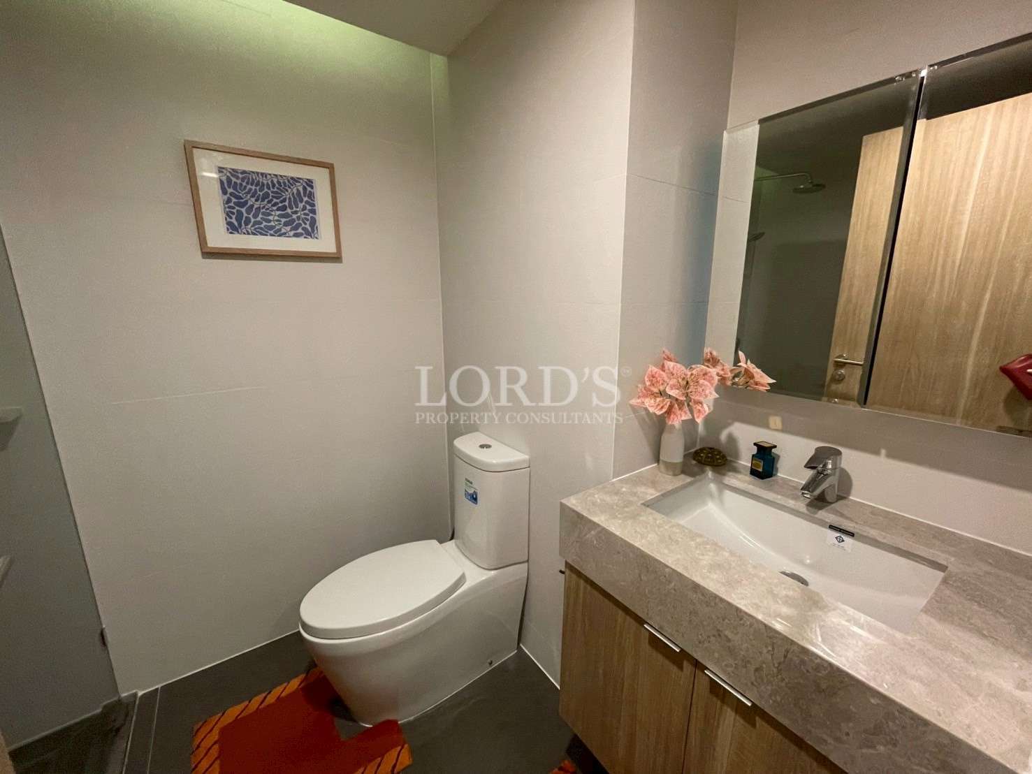 Modern bathroom with toilet, vanity sink, mirror cabinet, and soft ambient lighting.