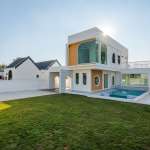 Modern two-story villa with private pool, large windows, and landscaped green lawn