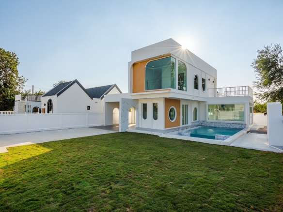 Modern two-story villa with private pool, large windows, and landscaped green lawn