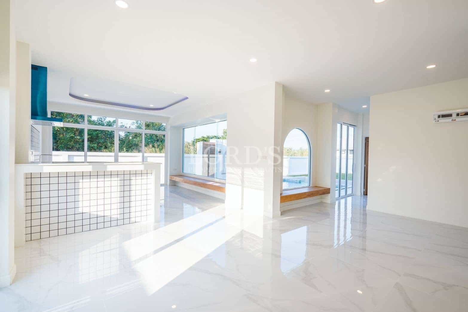 Bright open-plan living space with modern kitchen, large windows, and glossy white flooring