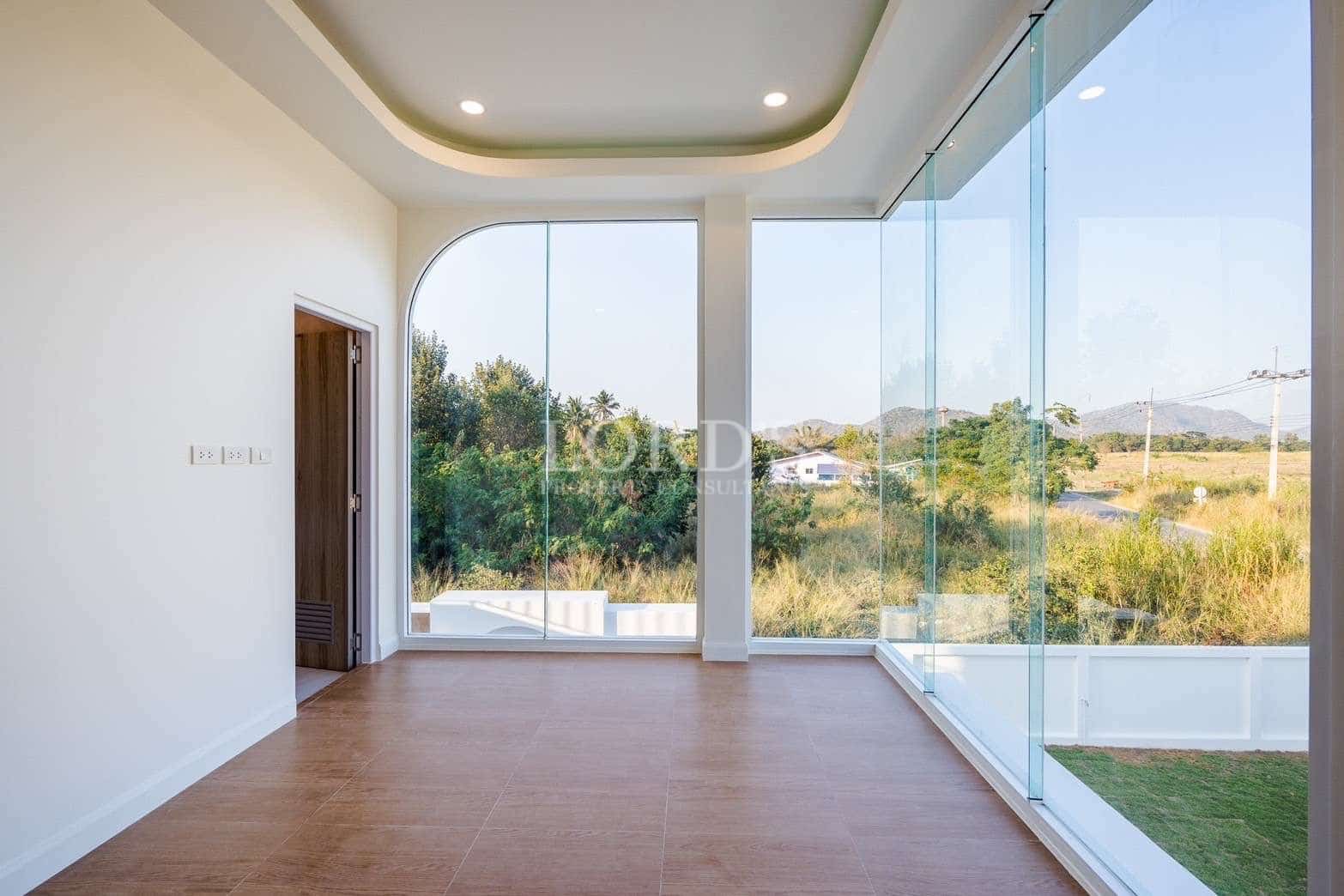 Bright empty room with floor-to-ceiling glass walls and panoramic nature views