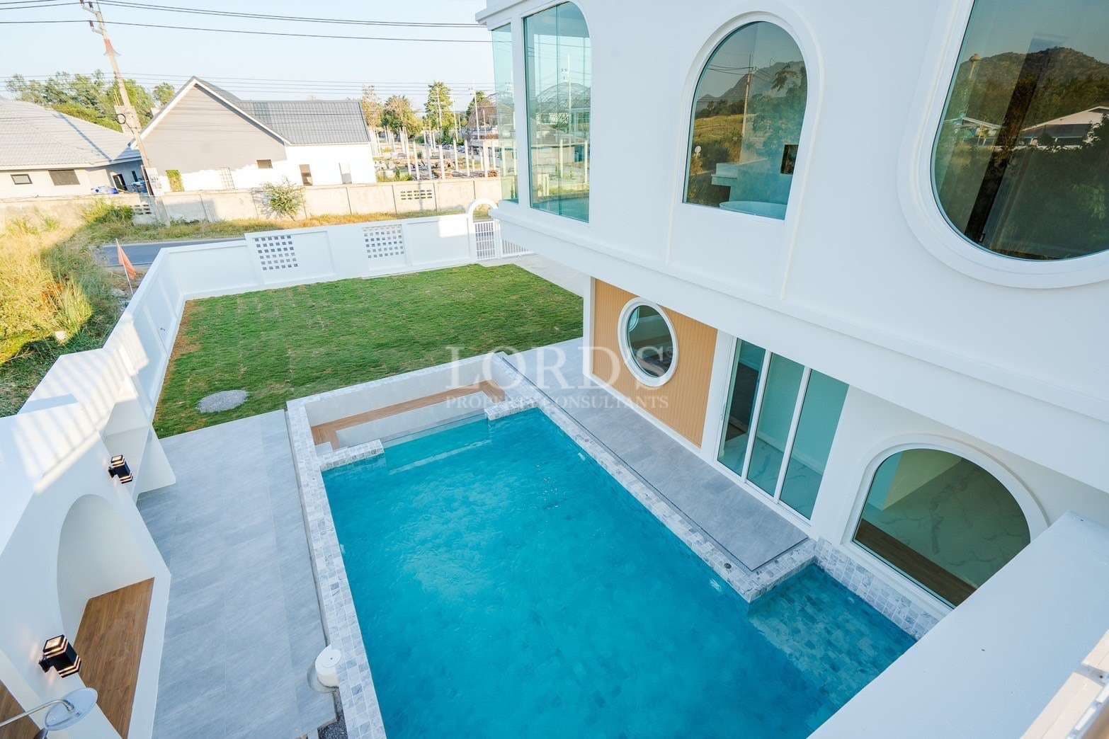 Modern two-story villa with private swimming pool, lawn, and arched windows