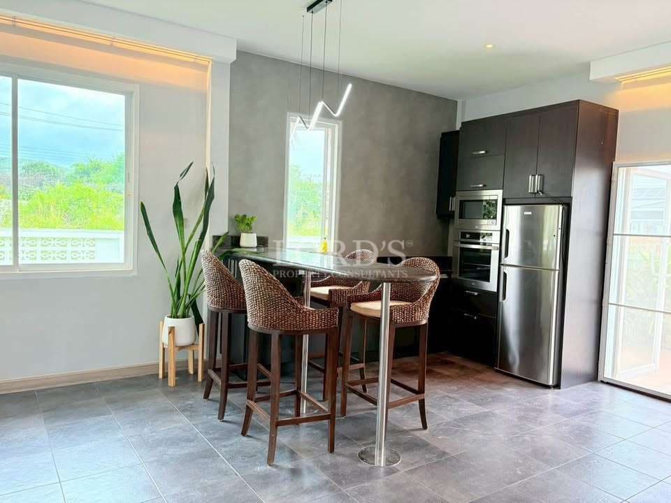 Modern kitchen with dark cabinets, stainless steel appliances, and a small dining island with bar stools.