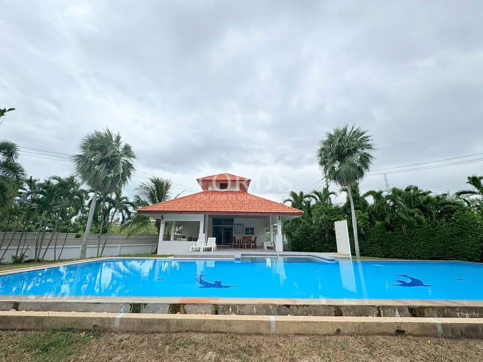 Large outdoor swimming pool with pavilion and palm trees