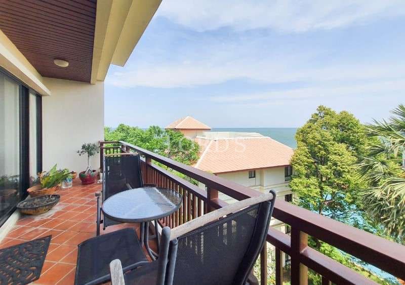 Private balcony with outdoor seating, ocean view, and surrounding greenery