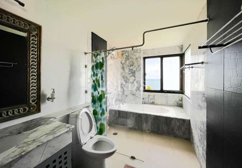 Spacious bathroom with bathtub, marble walls, glass window, and modern fixtures