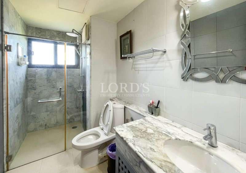Modern bathroom with walk-in glass shower, marble countertop vanity, and wall-mounted mirror