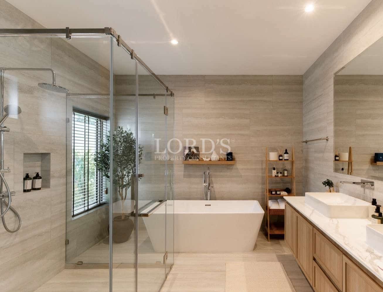 Modern luxury bathroom with glass shower enclosure, freestanding bathtub, and wooden vanity.