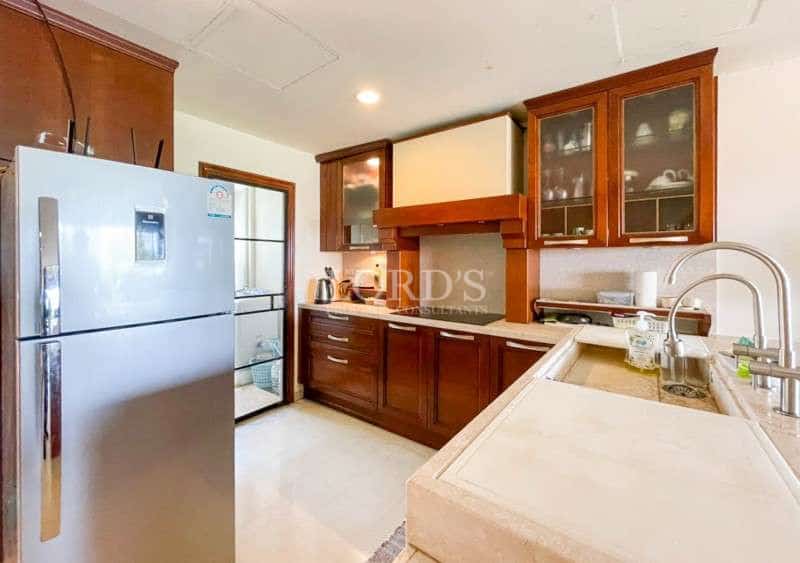 Modern kitchen with wooden cabinets, stainless steel refrigerator, and stone countertops