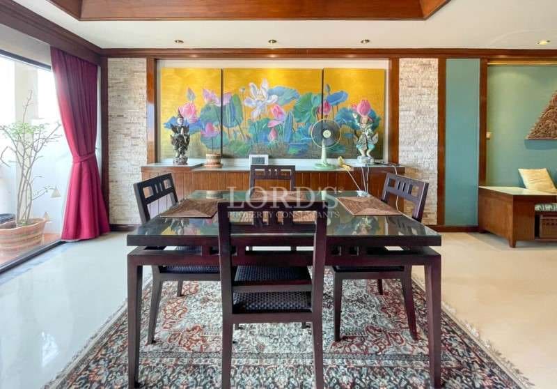 Elegant dining area with wooden table, glass top, decorative wall art, and natural light