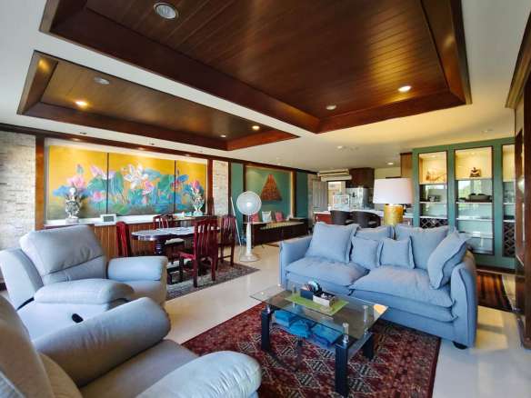 Open-plan living and dining area with wooden ceiling, modern sofas, and decorative wall art