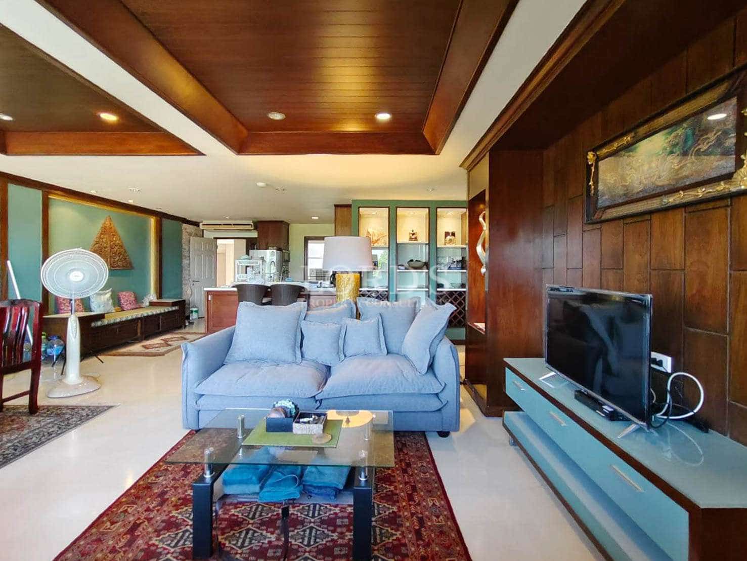 Spacious living room with wooden ceiling, modern sofa, TV unit, and open-plan layout