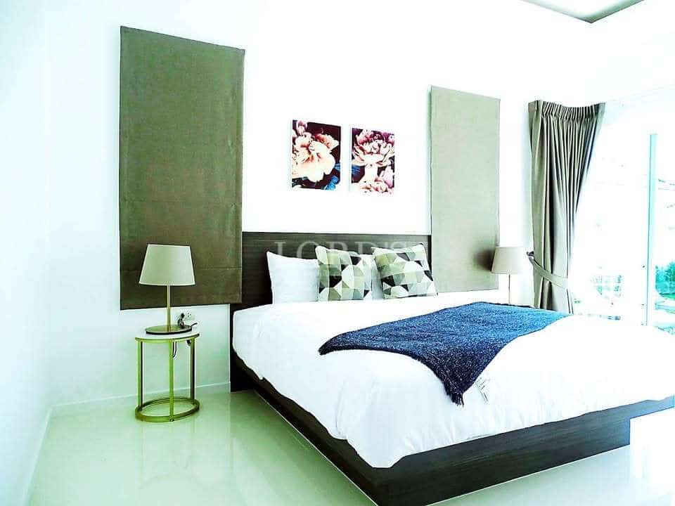Bright modern bedroom with double bed, accent wall panels, and bedside lamps