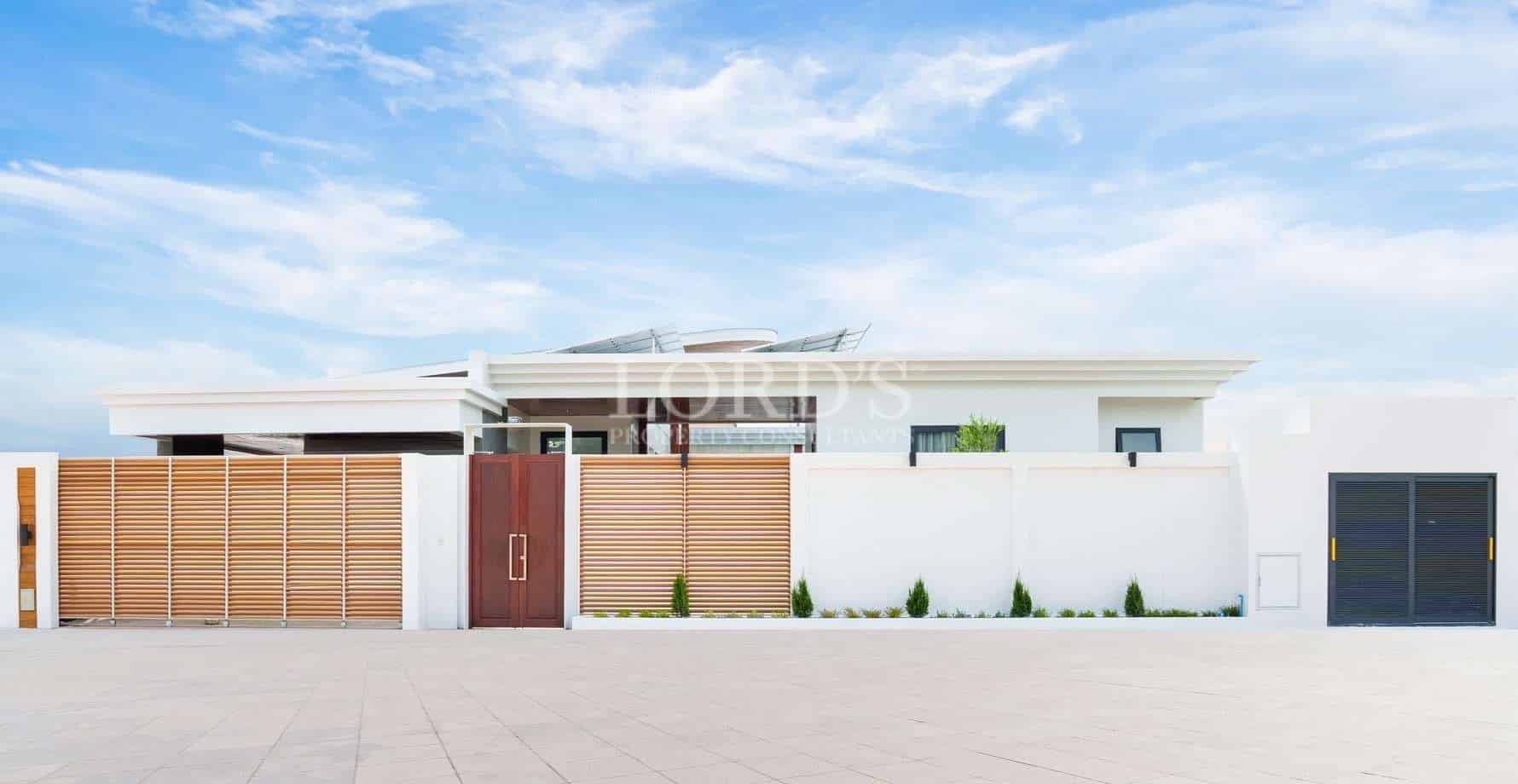 Modern villa exterior with white boundary wall, wooden slatted gate, and contemporary entrance design.