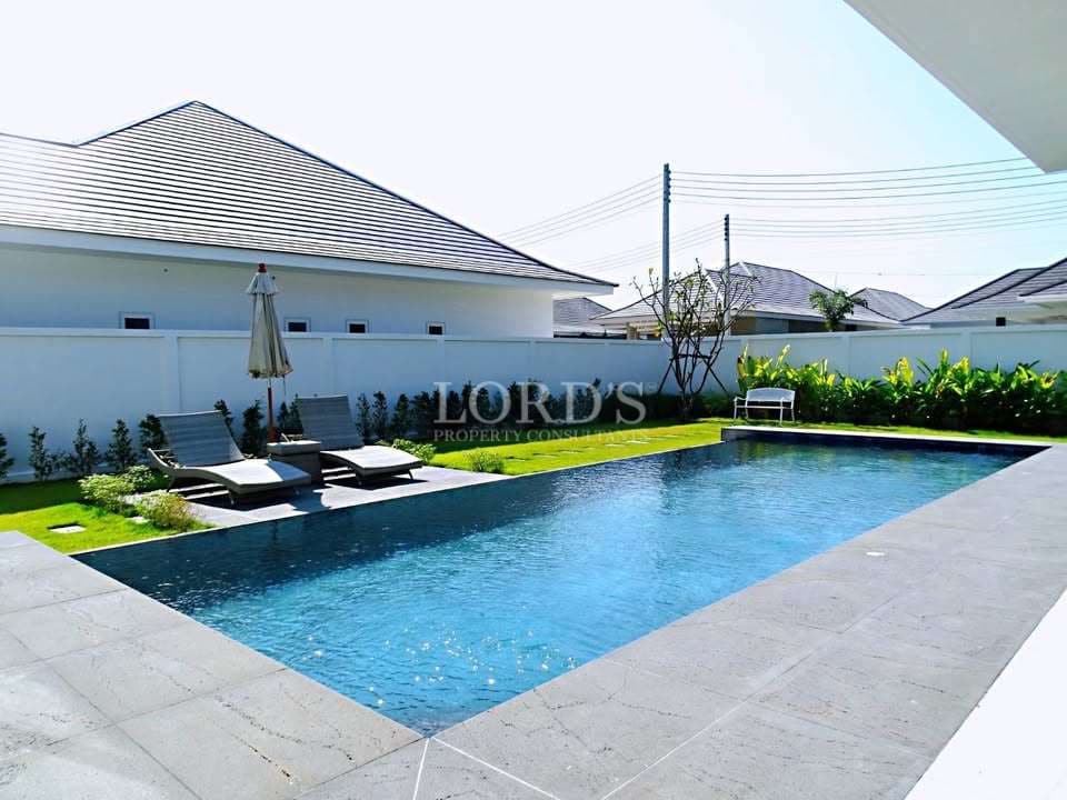 Private outdoor swimming pool with sun loungers and landscaped garden