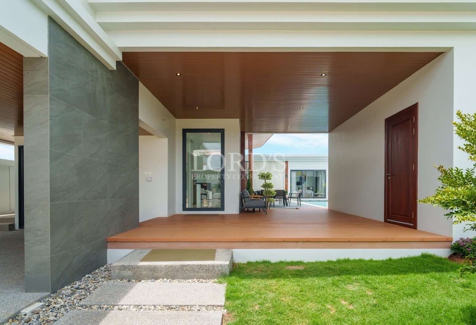 Modern house covered porch with wooden deck, contemporary exterior design, and garden view.