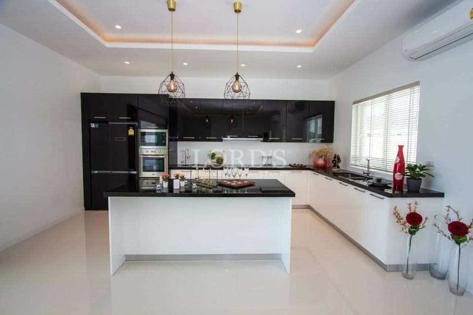 Modern luxury kitchen with black and white cabinets, island counter, and pendant lights