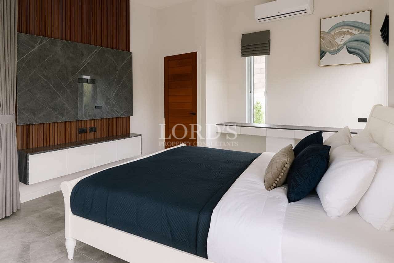 Modern bedroom with wall-mounted TV unit, white bed frame, and minimalist interior design