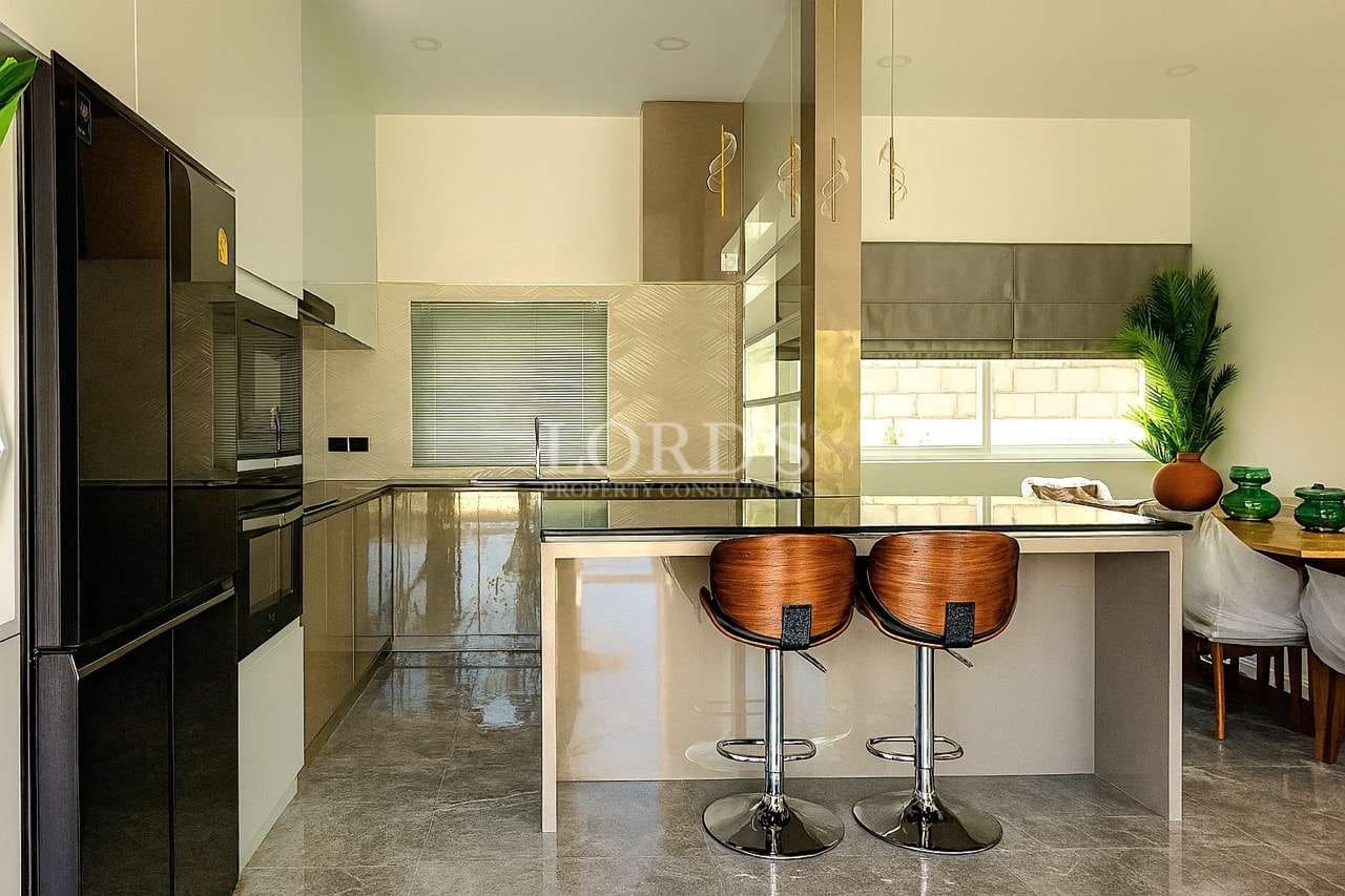 Modern luxury kitchen with island counter, bar stools, built-in appliances, and elegant neutral design