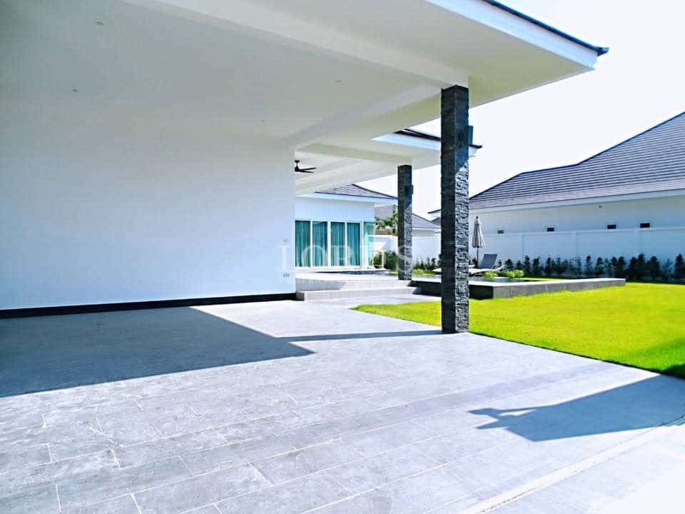 Modern house exterior with covered patio, stone pillars, and green lawn