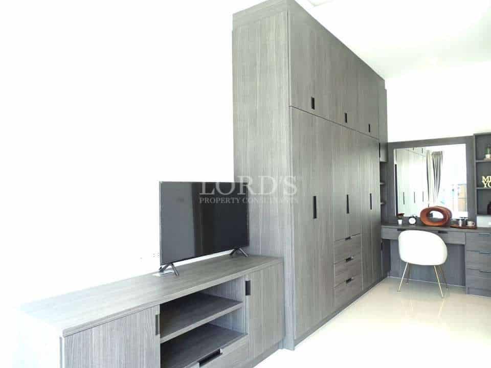 Modern bedroom storage area with built-in wardrobe, TV unit, and vanity desk