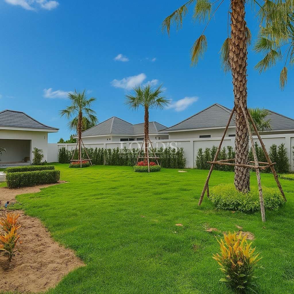 Landscaped garden with green lawn and palm trees inside a luxury residential villa compound.