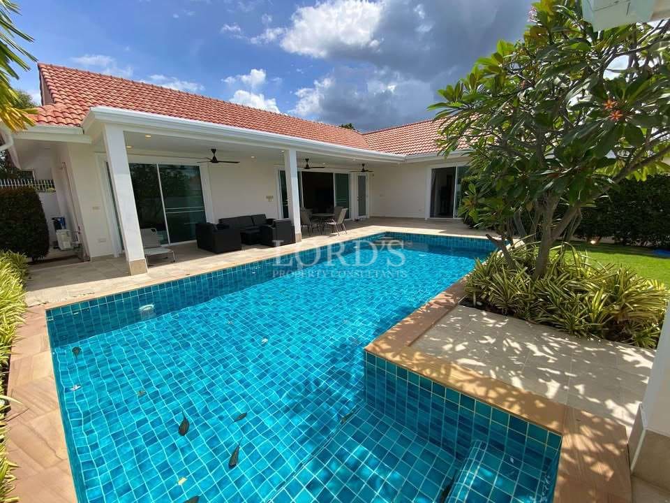 Luxurious poolside villa with greenery.